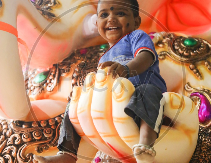 A Kid Sat in a Lord Ganesh Idol Hand