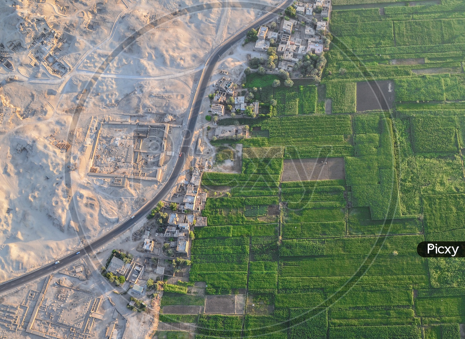 Aerial shot of half Azab Desert (non cultivated lands) and half agricultural lands in Luxor, Egypt taken from the hot air balloon.  Ruins of historical buildings can been seen on the left side of the picture.
