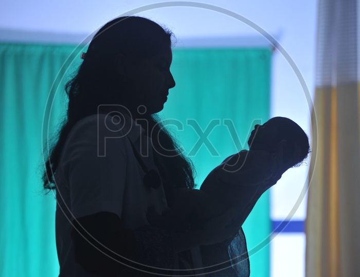 Silhouette of Doctor Holding New Born Baby Child In Arms