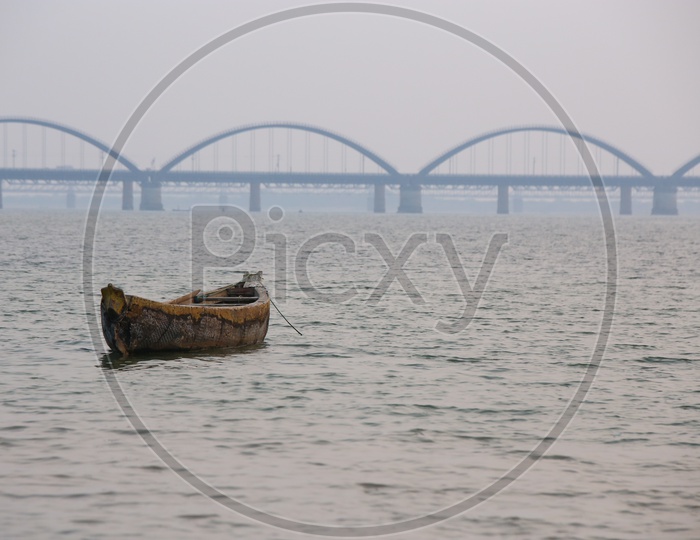 A Lone Fisher Boat On River Godavari With Arch Bridge In Background