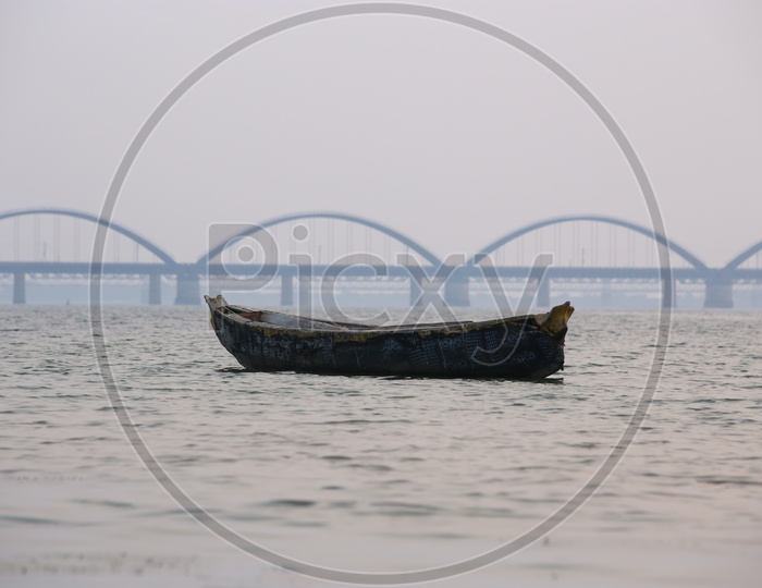 A Lone Fisher Boat On River Godavari With Arch Bridge In Background