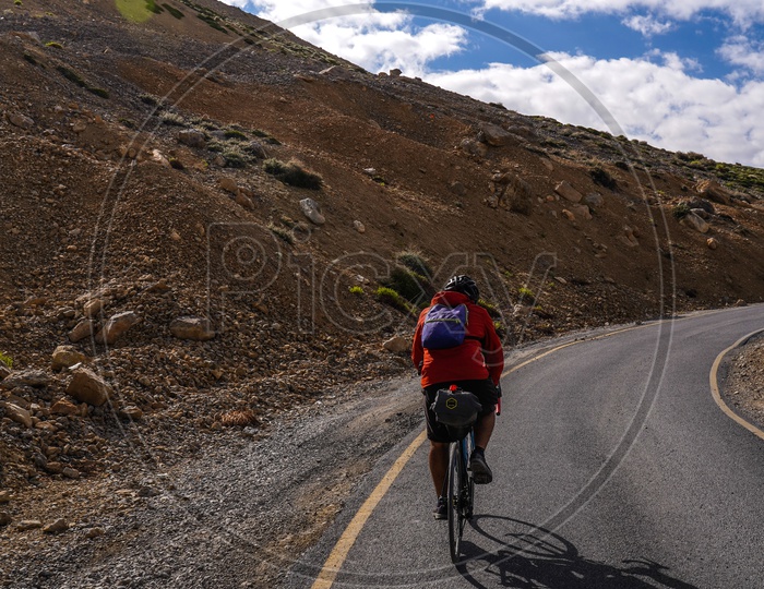 Cyclist  Riding Cycle bike  on The Valley Roads of Leh With a View Of Snow Capped Mountains