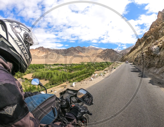 An Adventurer Tourist Biker On the Valley Roads Of Leh With a View Of Snow Capped Mountains