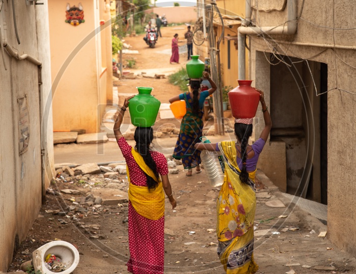 Woman carrying water vessels on top of their heads in Urban city for water scarcity