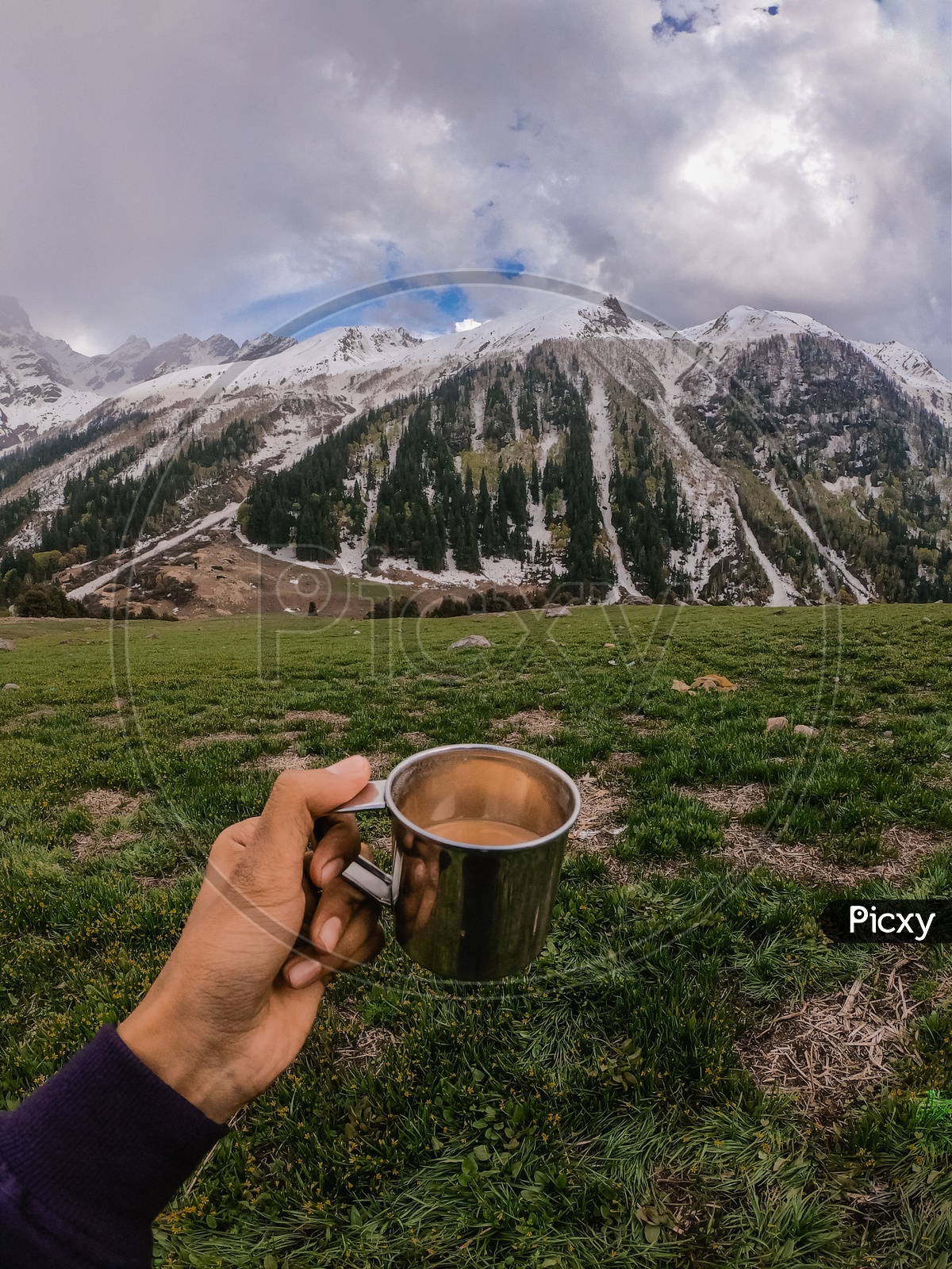 A Trekker Adventurer With a Tea Cup In Hand With a View Of Snow Capped Mountains In  Background