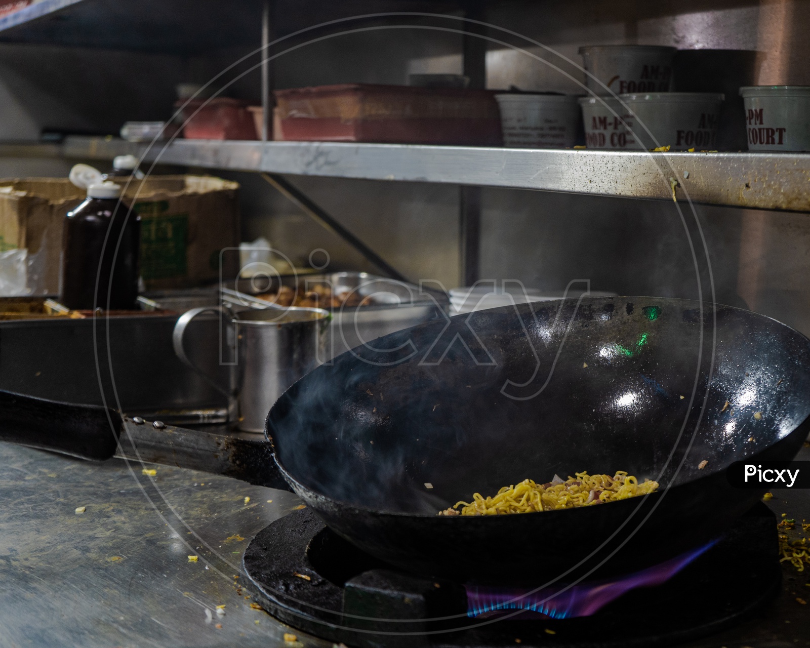 Noodles being cooked in a wok with smoke