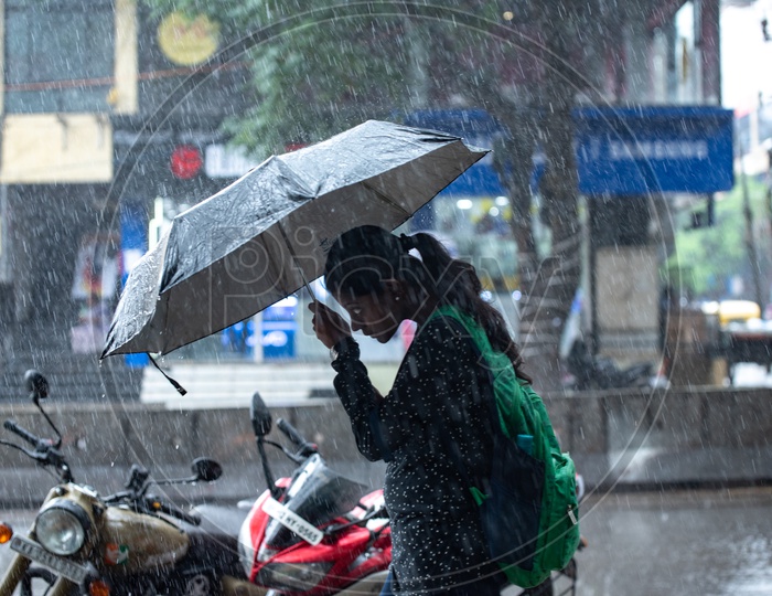 A woman walking in heavy rain with an umbrella in Koramangala Bangalore