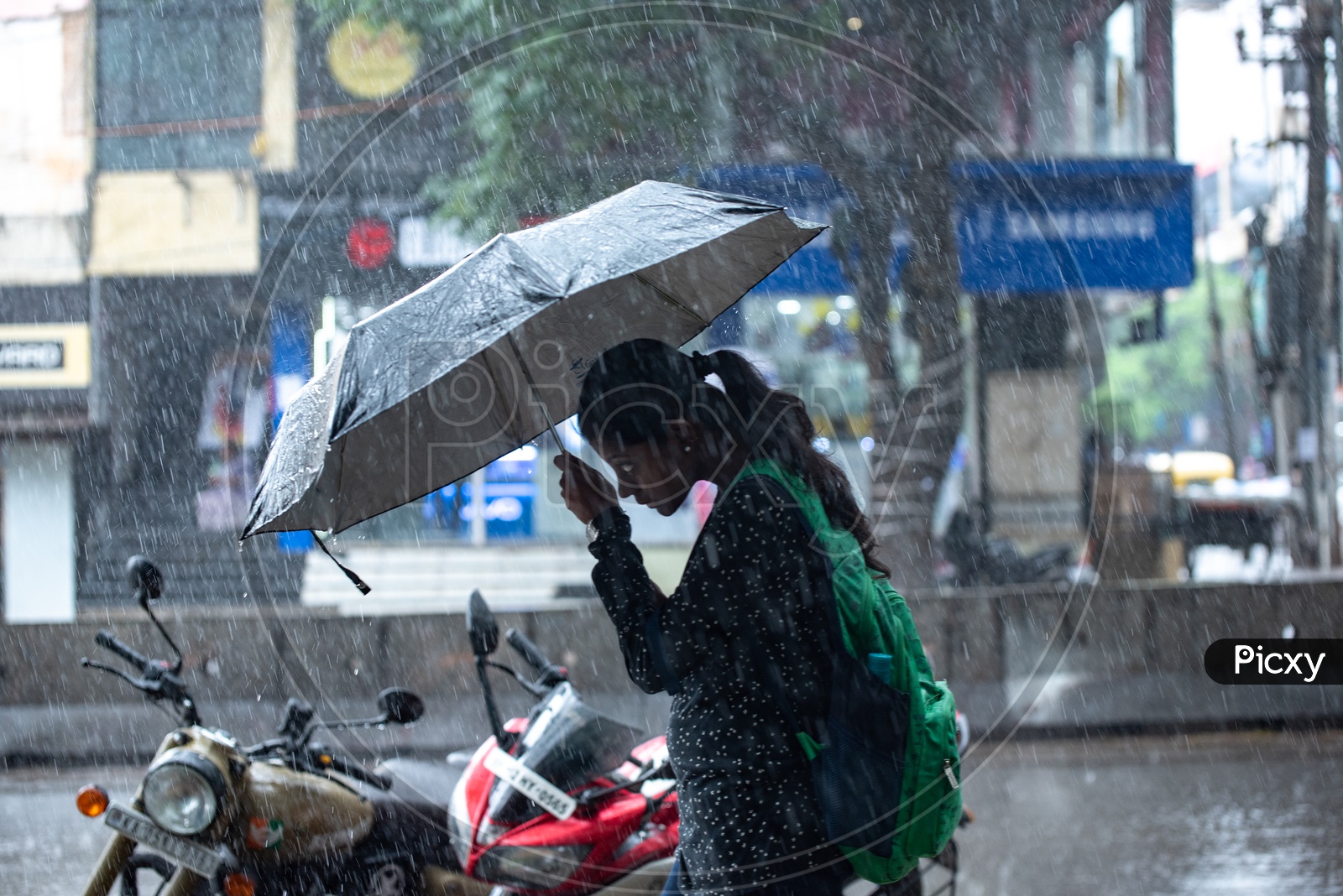 A woman walking in heavy rain with an umbrella in Koramangala Bangalore