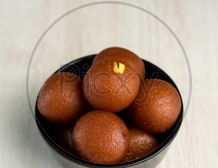 Gulab jamun  Indian Sweet Served In a Black Ceramic Bowl on an Wooden Background