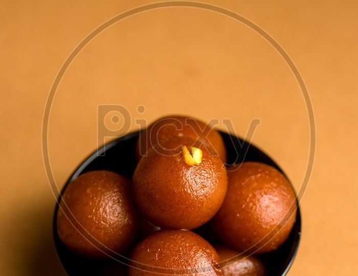 Gulab jamun Indian Sweet or dessert or savourie Served In a black Ceramic Bowl on an Wooden Background