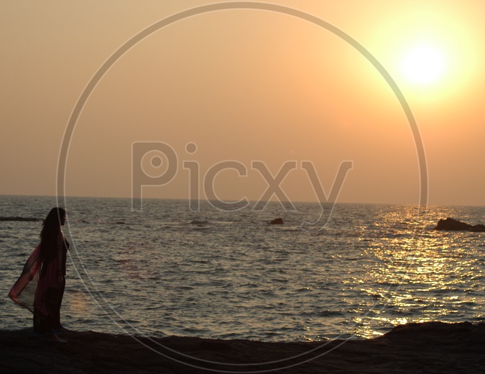Young Woman at the beach watching Sunset