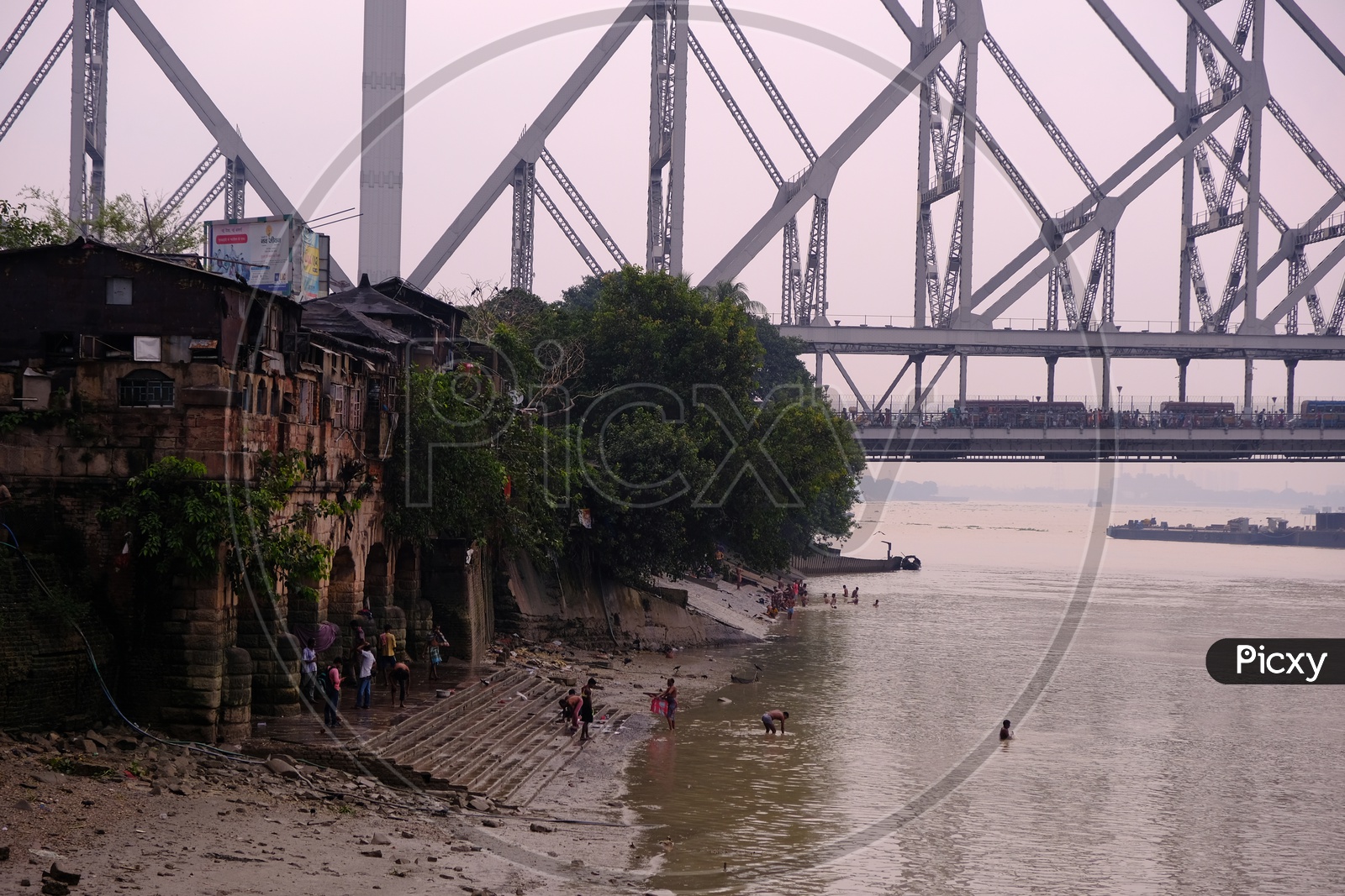 People Taking Dip in Hooghly River with Howrah Bridge in Background