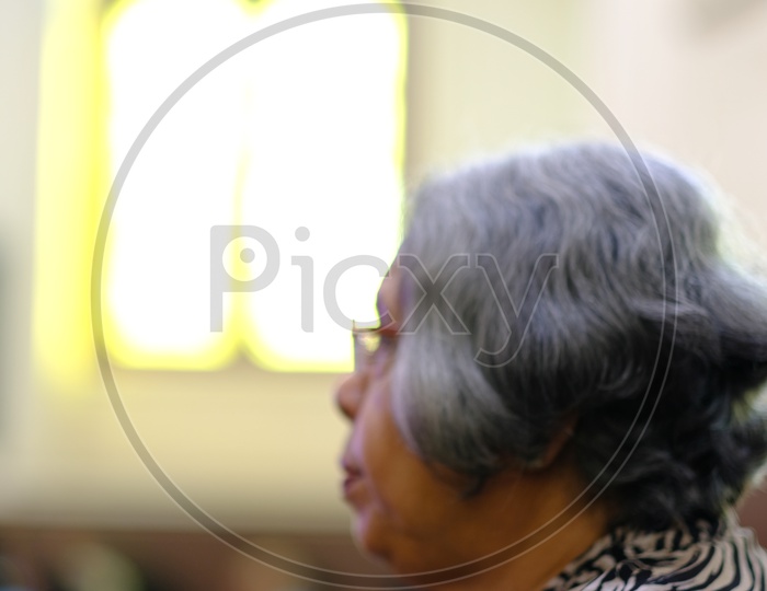 old Woman Christian devotee Offering Prayers In a Church