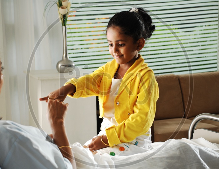 Girl Child Playing With a Woman on Hospital Bed