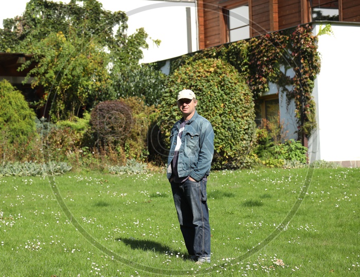 Young Man Wearing Cap And Standing In a Lawn Garden