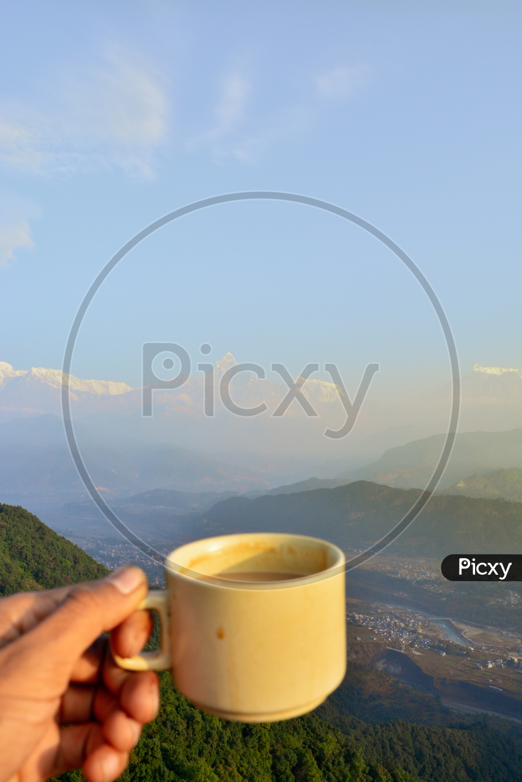 A Man Holding a Tea Cup Over a Valley View Landscape