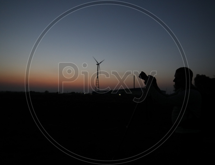 Silhouette Of a Photographer With Wind Mills In Background