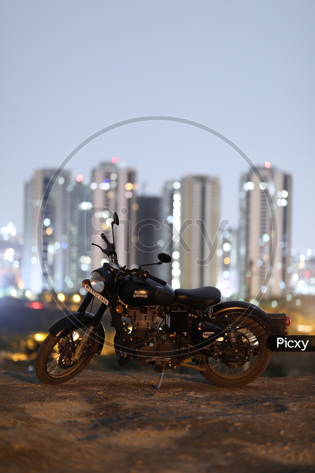 Royal Enfield Classic 350 Matte Black Bike On a Rock Hill With City High Rise Building  Bokeh in Background