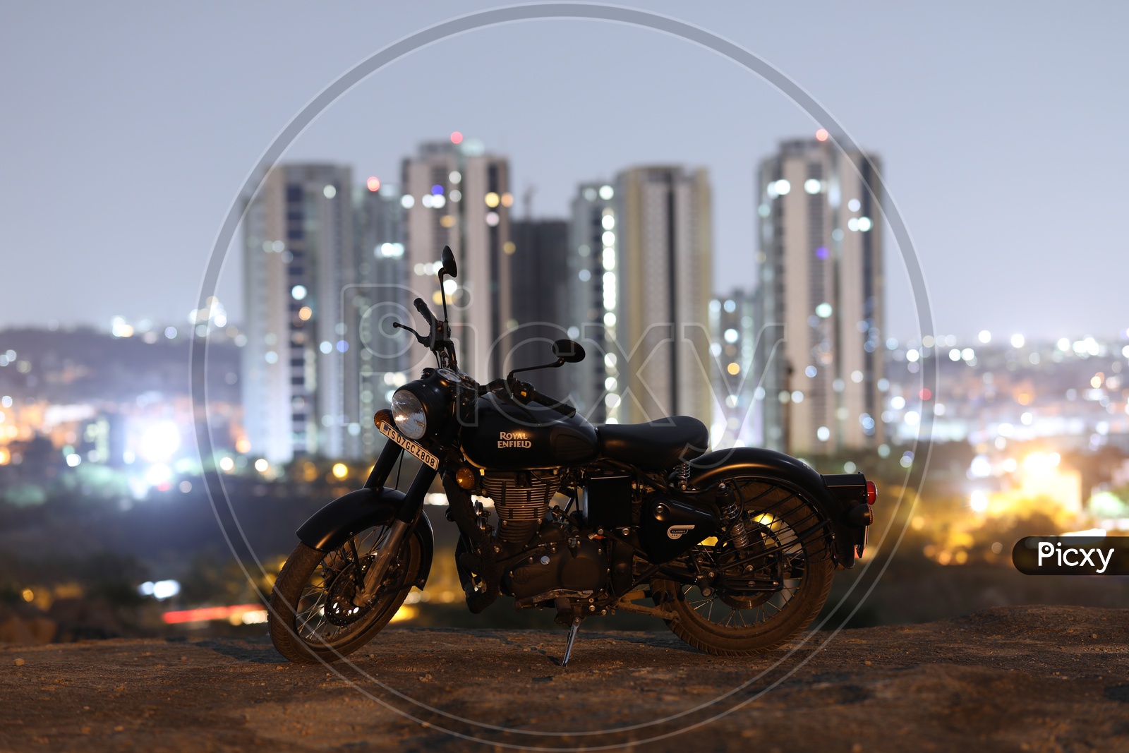 Royal Enfield Classic 350 Matte Black Bike On a Rock Hill With City High Rise Building  Bokeh in Background