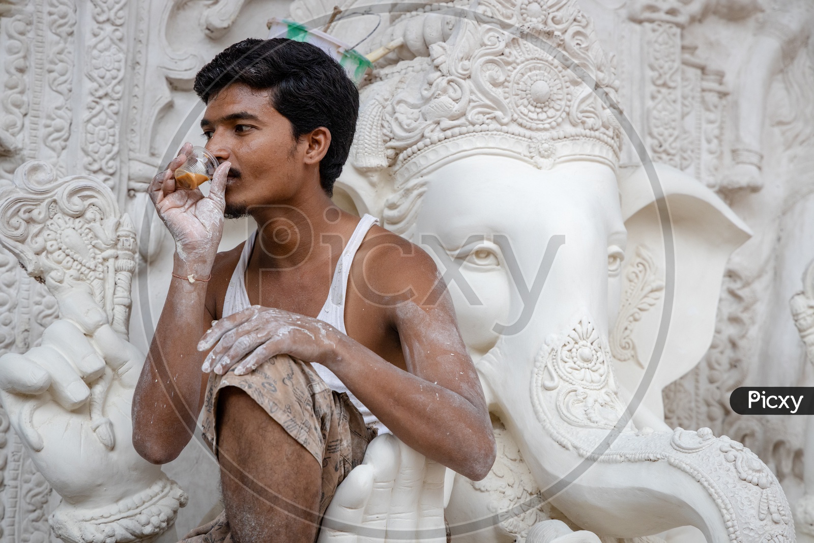 A Worker Artist Having Tea While Carving  Ganesh idols  in workshops