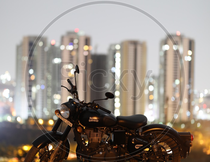 Royal Enfield Classic 350 Matte Black Bike On a Rock Hill With City High Rise Building  Bokeh in Background