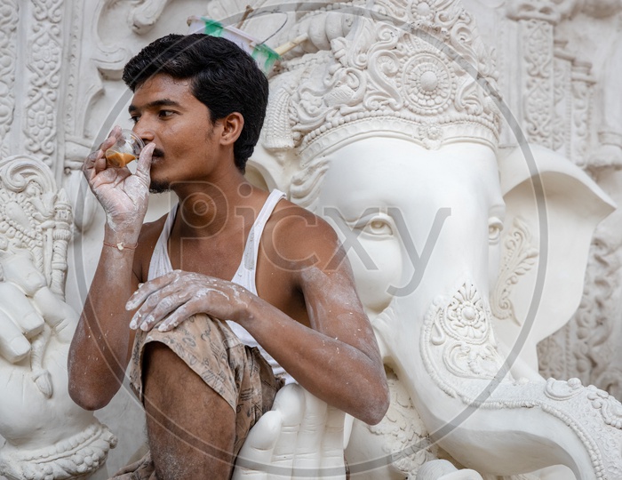 A Worker Artist Having Tea While Carving  Ganesh idols  in workshops