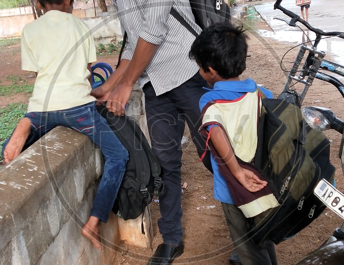 A volunteer helping the child in lifting his school bag