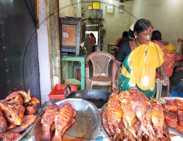 Woman selling the fried fishes which are  freshly caught