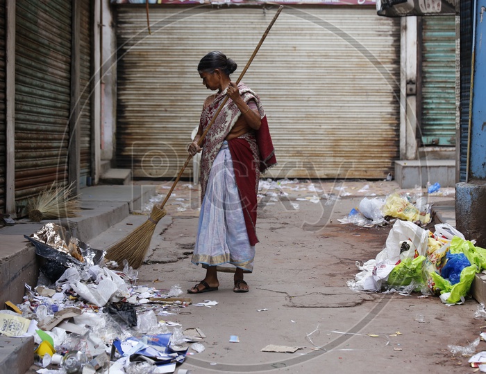 Sanitary Worker Sweeper Sweeping The Streets filled with plastic.