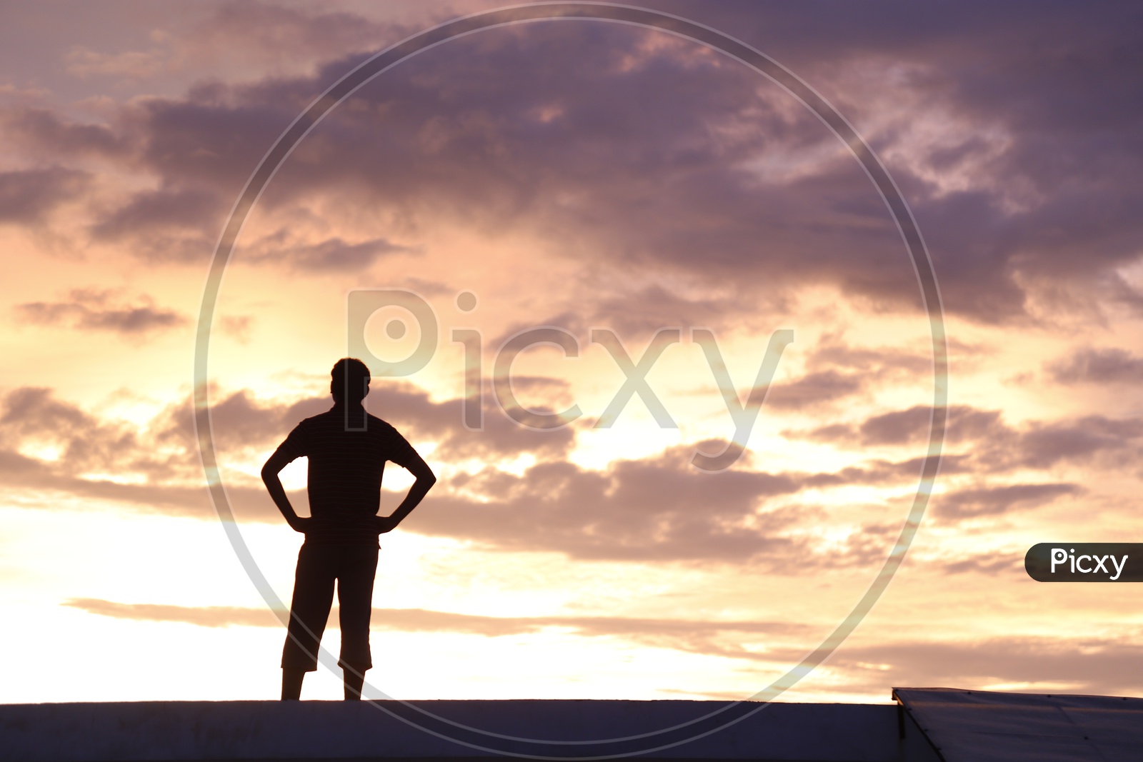 Silhouette Of a Young Man Standing Alone  Over a Sunset Sky
