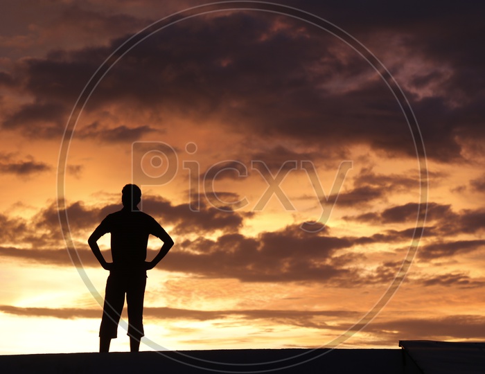 Silhouette Of a Young Man Standing Alone  Over a Sunset Sky