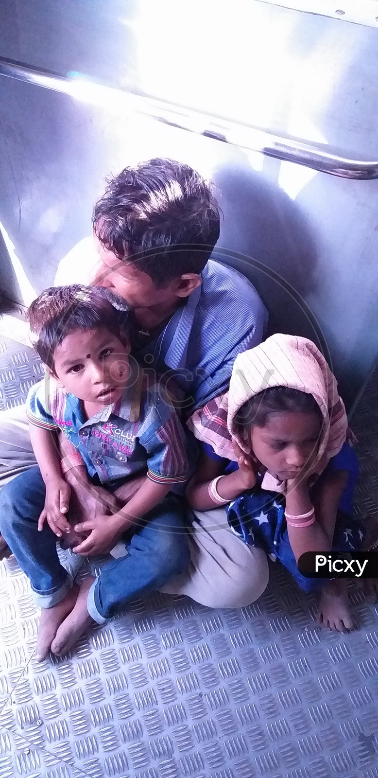 A Man with his children travelling  in a MMTS train