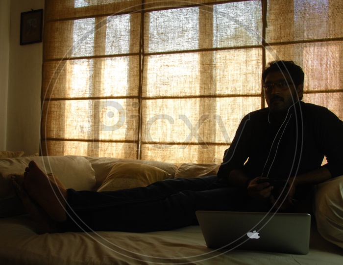 Silhouette Of a  Man Using Laptop In a House Over a Window
