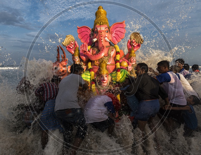 Big wave splashing against the Ganesh idol while immersing in the sea.