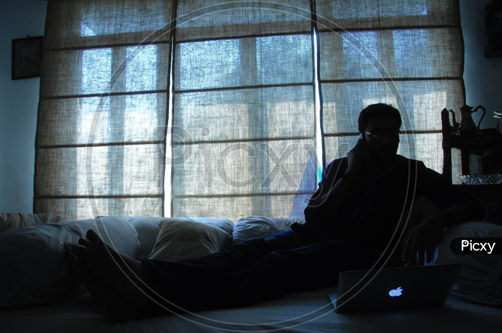 Silhouette Of a  Man Using Laptop In a House Over a Window
