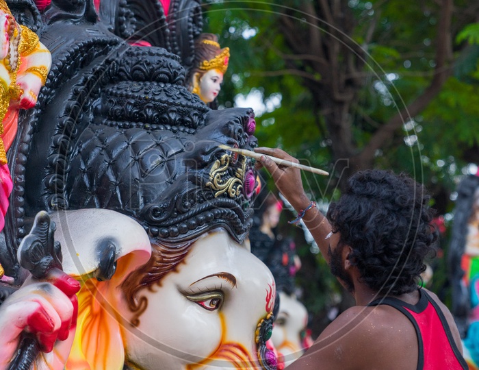 A person giving the final touches to the ganesha idol