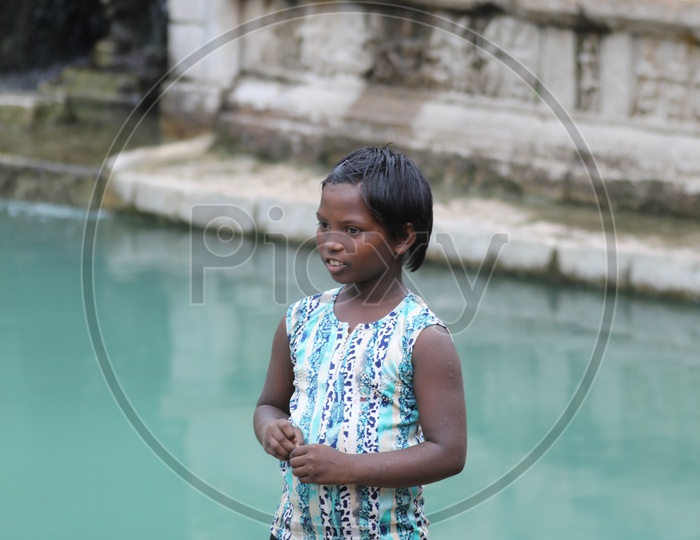 Indian Girl Child Standing At a Temple Tank