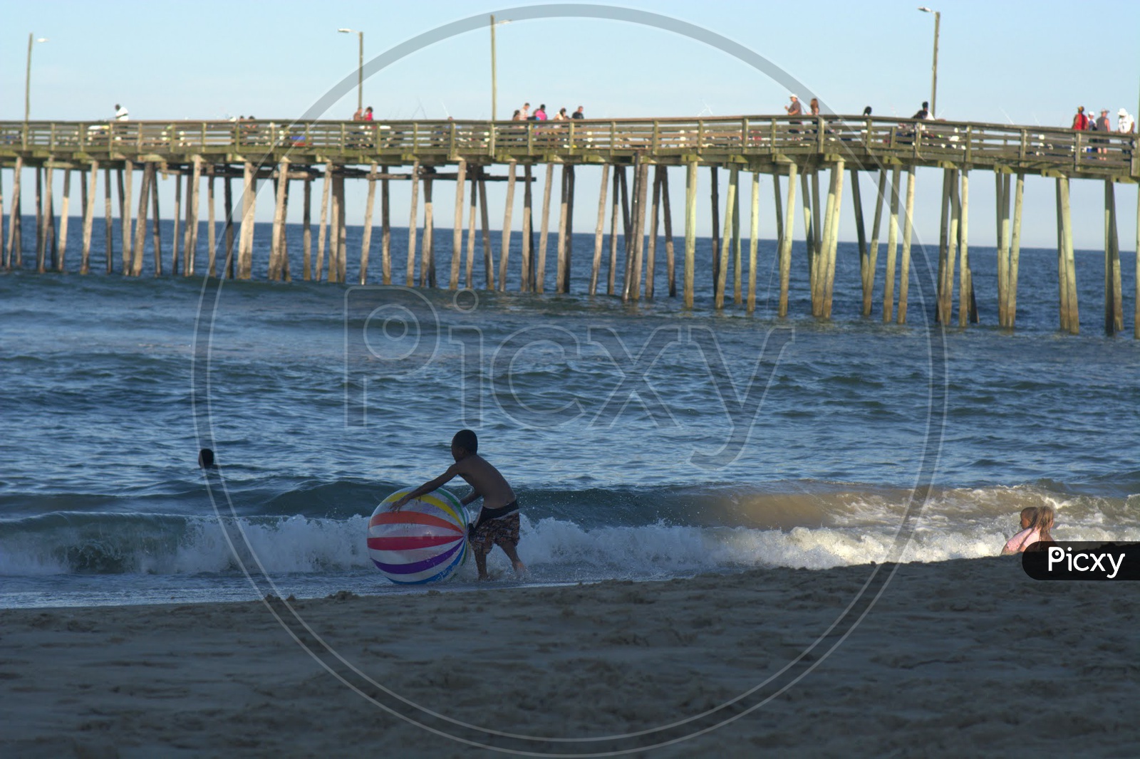 Kids Or Children Playing  on Beach With a Pier into Sea or Ocean