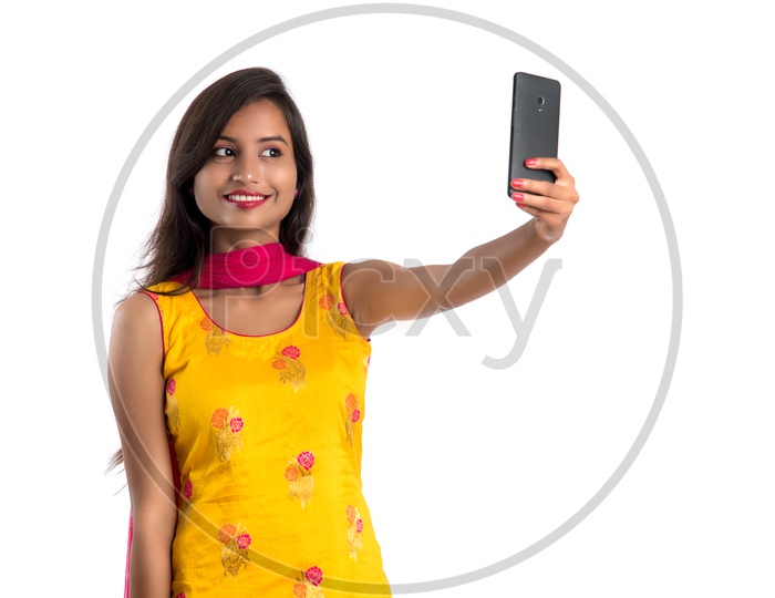 Young Indian Girl or Woman Taking Selfie With a Smartphone  On an Isolated White Background