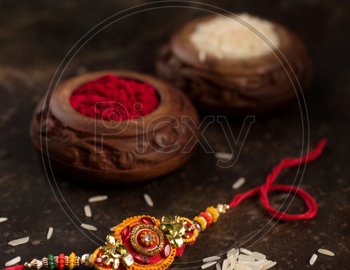 Rakhi With Vermilion or Kumkum Bowl And Rice Grains on a Textured Background For Rakhi Or Raksha Bandhan Festival
