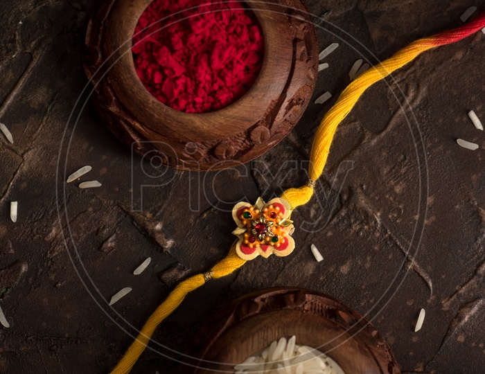 Rakhi Or Elegant Rakhi With Rice Grains Kumkum Bowl  On an Textured Background For Raksha bandhan Festival