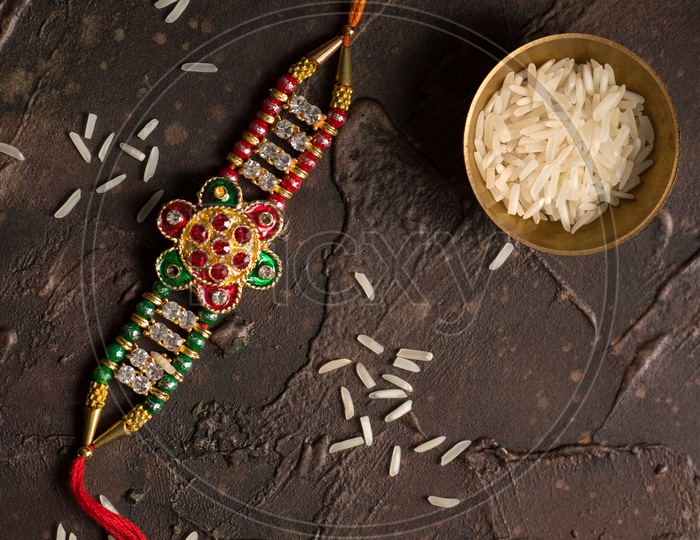 Rakhi Or Elegant Rakhi With Rice Grains Kumkum Bowl on an Textured Background For Raksha Bandhan Festival