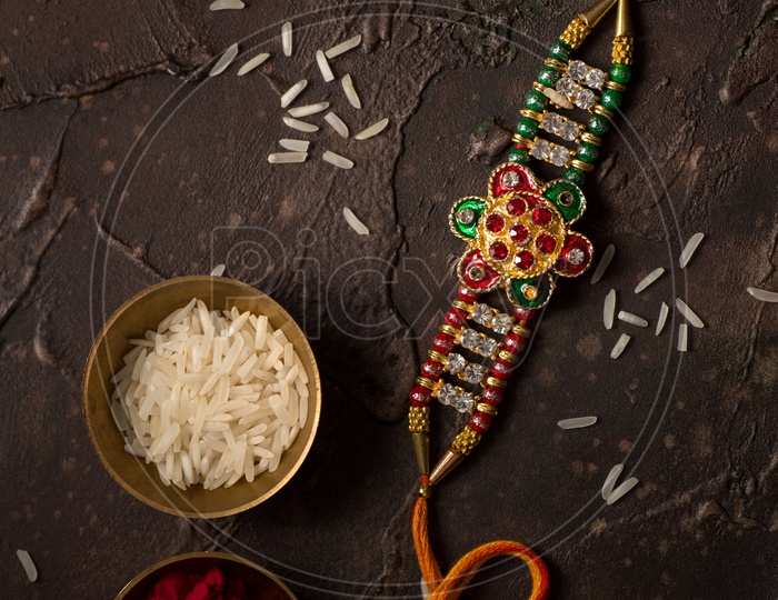 Rakhi Or Elegant Rakhi With Rice Grains Kumkum Bowl on an Textured Background For Raksha Bandhan Festival