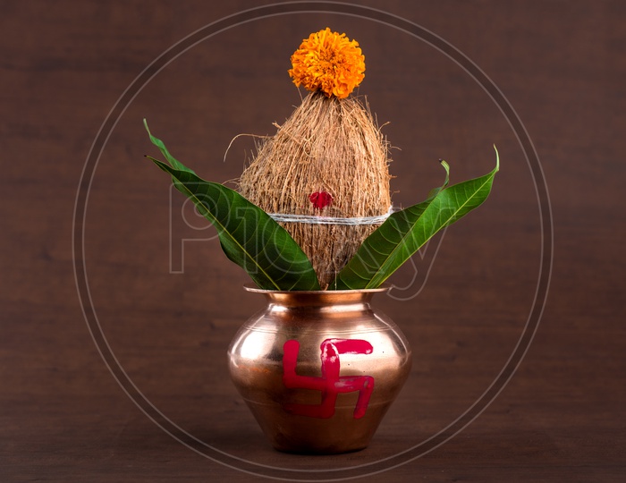 Copper Kalash  With Dried Coconut , Mango Leafs And Floral Decoration For Hindu Pooja or Puja  Essentials  on an Wooden Background
