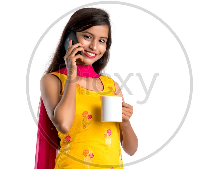 Young Indian Woman Or Girl  Speaking in Mobile Or Smartphone With Coffee Cup In Hand On an Isolated White Background