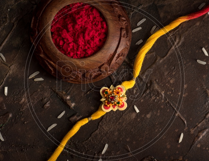 Rakhi Or Elegant Rakhi With Rice Grains Kumkum Bowl  On an Textured Background For Raksha bandhan Festival