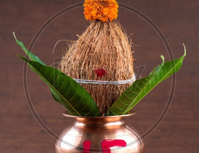 Copper Kalash  With Dried Coconut , Mango Leafs And Floral Decoration For Hindu Pooja or Puja  Essentials  on an Wooden Background