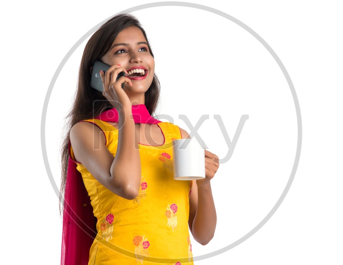 Young Indian Woman Or Girl  Speaking in Mobile Or Smartphone With Coffee Cup In Hand On an Isolated White Background