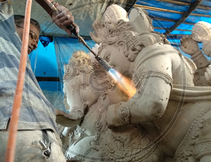 Prepartion of Ganesh Idol for Ganesh Chathurthi. After Applying some wet grass and  Clay A man heating them to get strong, Ganesh Mould, Ganesh preparing by plaster of paris, Preparing of Ganesh Idol for Ganesh Chathurthi