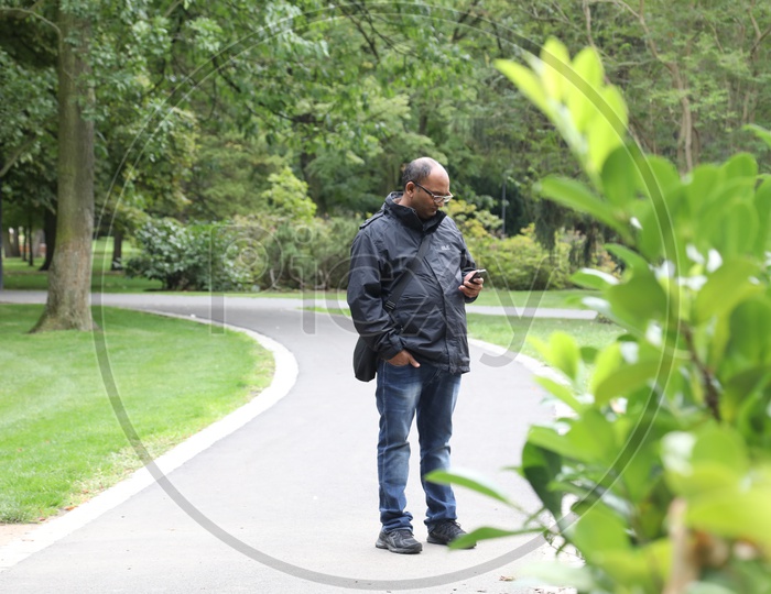 An Indian Man Using Mobile Phone In a Park